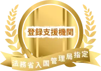 Golden emblem with laurel wreath and ribbon on black background. Central text in Japanese reads “登録支援機関,” conveying a sense of prestige and official recognition.